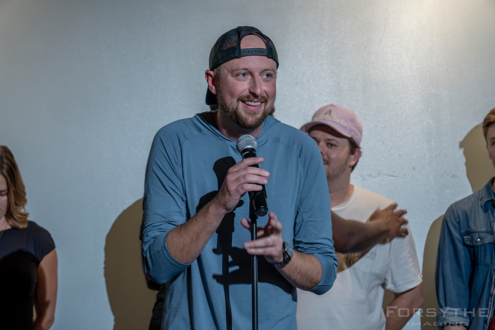 Host smiling at the mic stand at Arizona After Dark